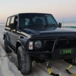car broken down at sunset on beach with tow straps attached