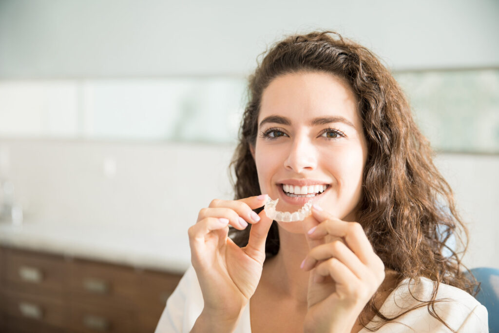 women holding Invisalign liners and smiling